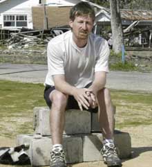 Patrick Wright sits in the dirt lot where his house once stood and where Bush vowed to