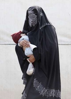 A woman wearing a black burqa holds her baby while waiting to receive a medical check-up at a make-shift military clinic for internally displaced persons (IDPs) in Dera Ismail Khan, located in Pakistan's restive North West Frontier Province on November 10, 2009.