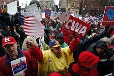 People in a large crowd wave signs and shout as labor unions and supporters, turned out in the rain outside New Jersey’s Statehouse in Trenton, N.J., Friday, Feb. 25, 2011, at a unity rally in support of Wisconsin workers locked in a battle over collective bargaining rights.