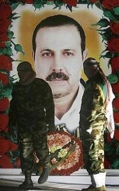 At a rally in Gaza, Hamas fighters stand in front of a portrait of Mahmoud Mabhouh