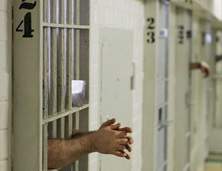 Prisoners reach through the bars in the F Cellhouse at the Oklahoma State Penitentiary where they are housed in old-fashioned cells with metal bars