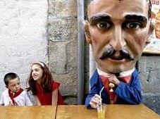 Children sit next to a 'cabezudo' (big head) during San Fermin's 'Comparsa de gigantes y cabezudos' (Parade of the giants and the big heads) in Pamplona on Thursday, 12 Jul 2007