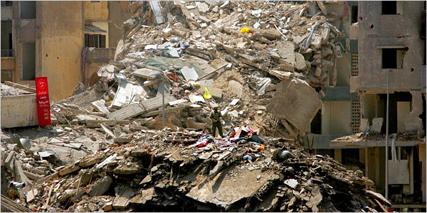 A man stood Wednesday on the site of a building in a southern suburb of Beirut destroyed by an Israeli attack. A sign, left, blamed the United States.