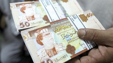 A banker shows 50 Libyan dinar bank notes bearing the portrait of ousted leader Muammar Gaddafi in Tripoli yesterday as people are refusing to use the bills and the banks are collecting them and returning them to the central bank.
