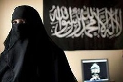 Malika El Aroud by her computer in her living room at her home in Brussels in April. The Arabic banner on the wall translates as: There is no God but Allah and Mohamed is his Messenger. (Hazel Thompson for The New York Times)